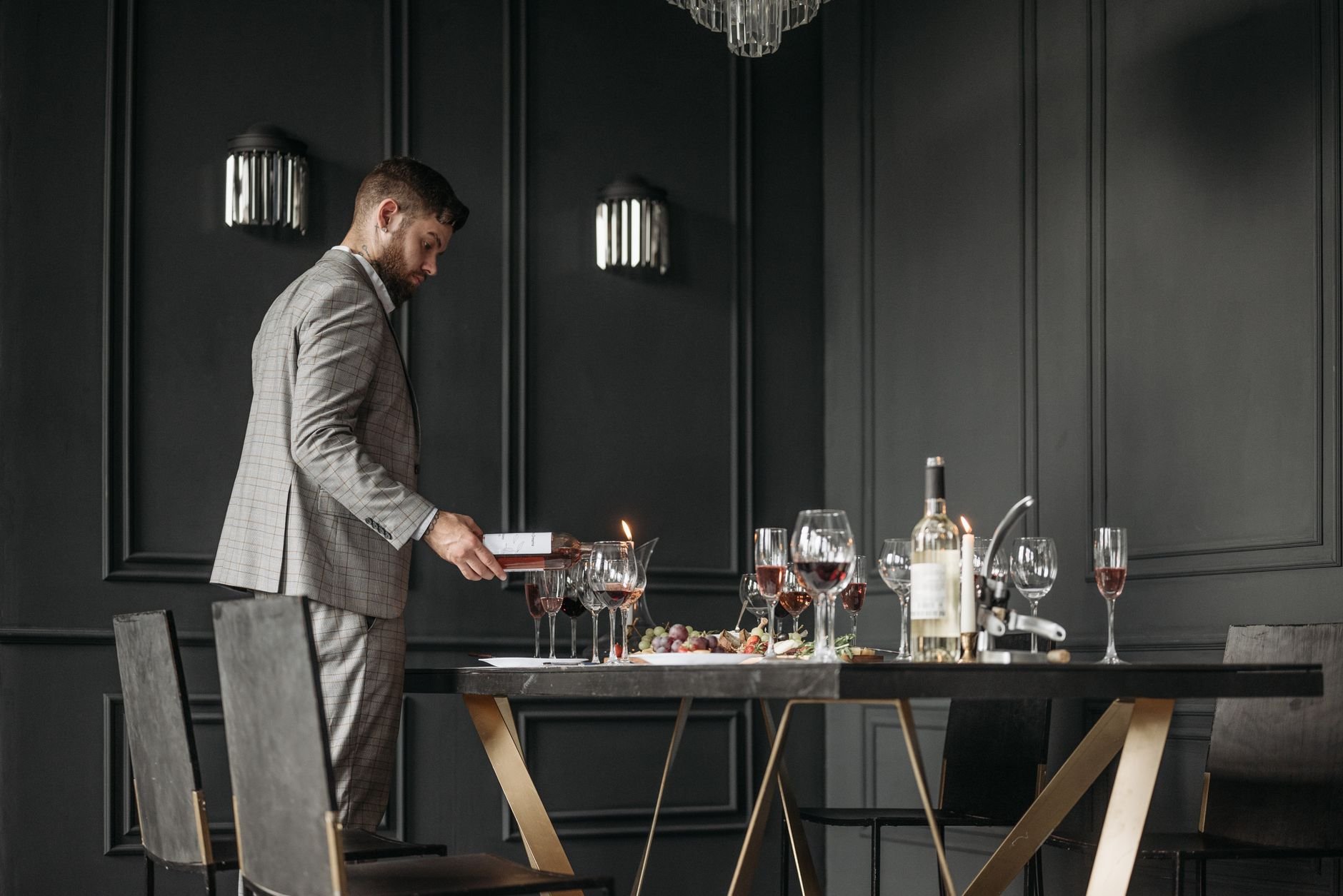 A sommelier preparing a wine tasting table with bottles and glasses in a stylish interior.